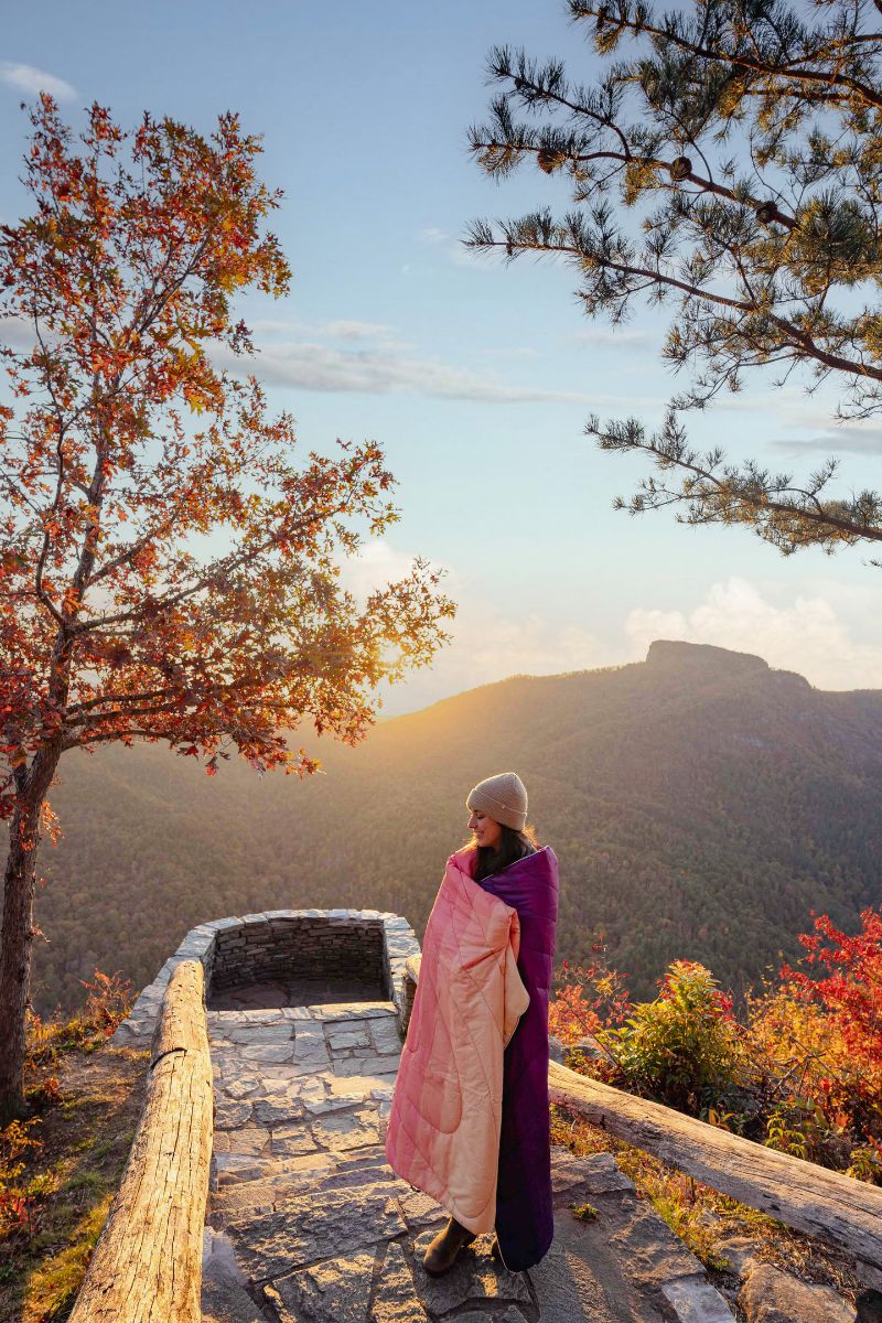 Woman wrapped in puffy blanket watching the sunrise 