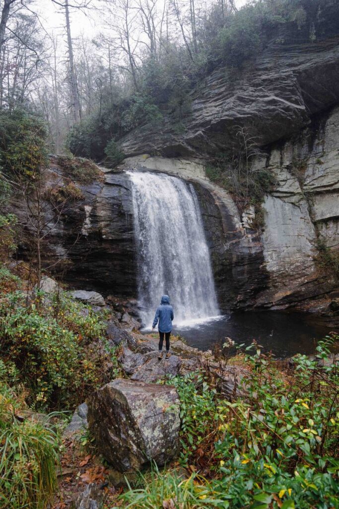 Woman in blue rain jacket standing in front of Looking Glass Falls